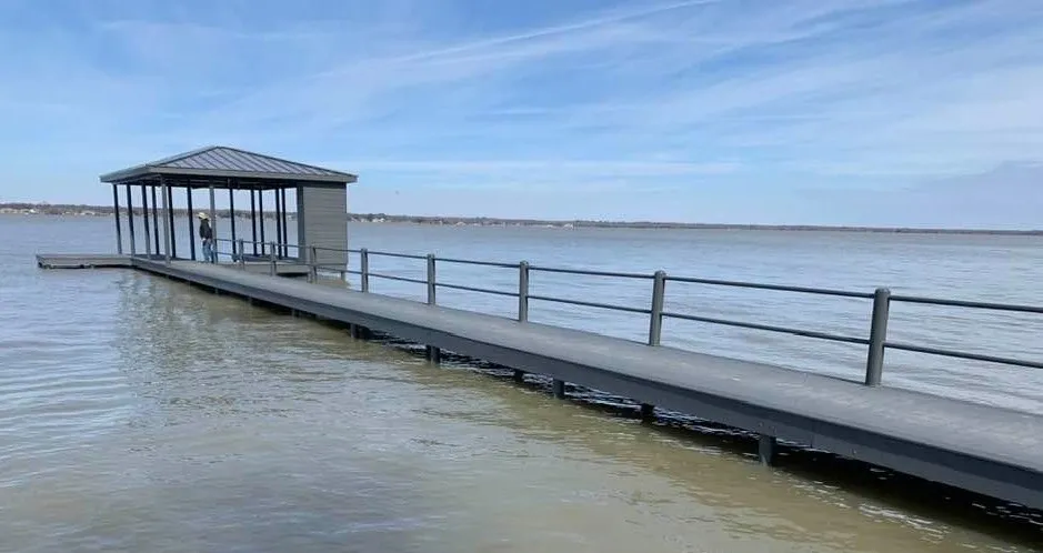A long deck leading to a dock where a man is standing under a covered roof