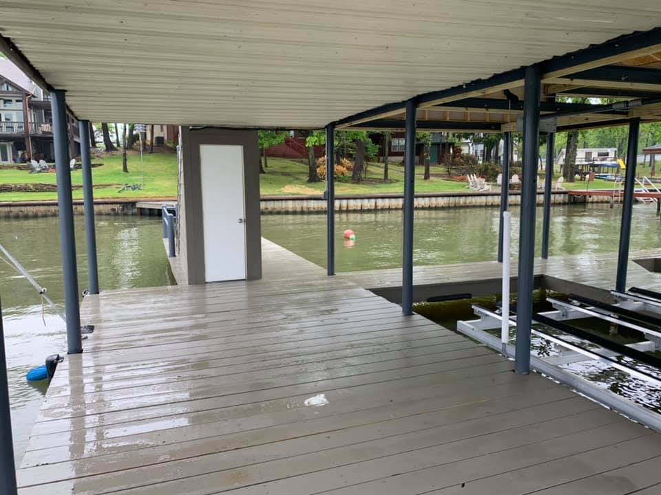 View from a double boat holding boat house deck facing the land with a white door behind the stairs in view